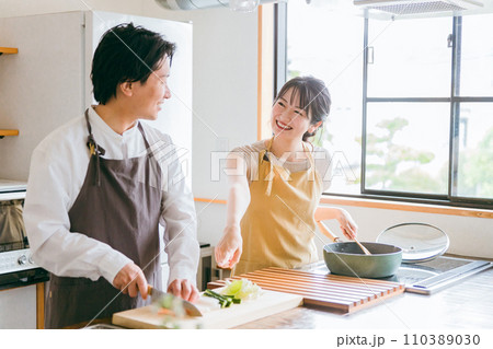 キッチンで料理をする夫婦・包丁で野菜を切る男性 キッチンで料理をする夫婦・包丁で野菜を切る男性 110389030