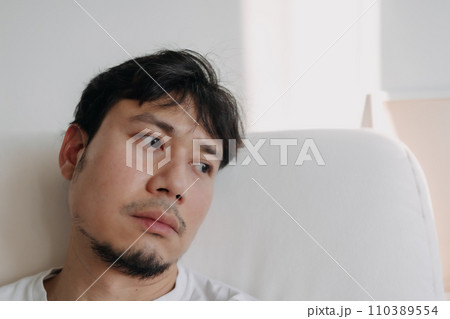 Close up face of lonely man feeling depressed and bored in low light room. 110389554