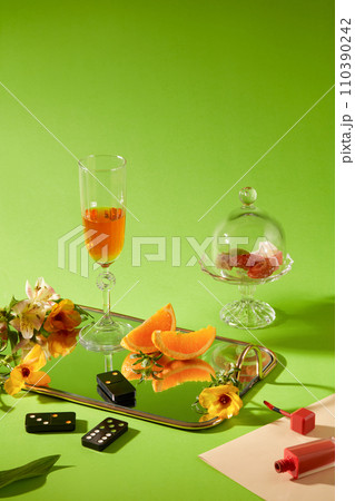 Green background with wine cups, fresh flower and domino set decorated. Space for design and presentation product Green background with wine cups, fresh flower and domino set decorated. Space for design and presentation product 110390242