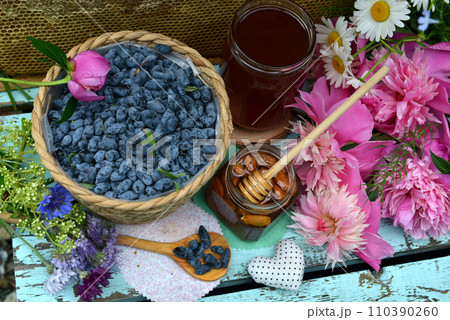 Still life with natural honey, honeycomb cut in pieces and honeysuckle berry with flowers on wooden background outside. Countryside summer rural background, vintage concept, healthy food 110390260