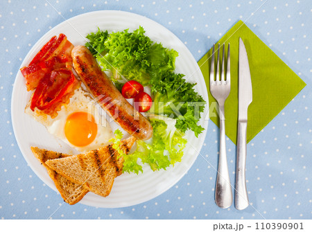 Top view of fried eggs with bacon, sausage and toasts Top view of fried eggs with bacon, sausage and toasts 110390901
