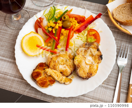 Oven baked hake with vegetable garnish 110390998