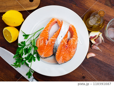 Fresh uncooked salmon fish with greens and lemon Fresh uncooked salmon fish with greens and lemon 110391087