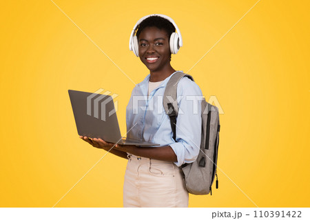 Glad young african american lady student in wireless headphones, use laptop, enjoy online lesson 110391422