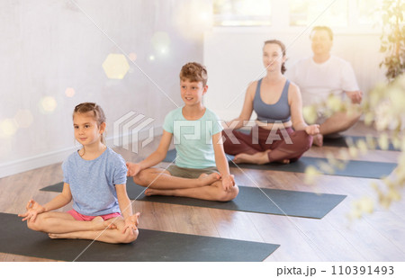 Child with family performs lotus pose, folding fingers in mudra of knowledge 110391493