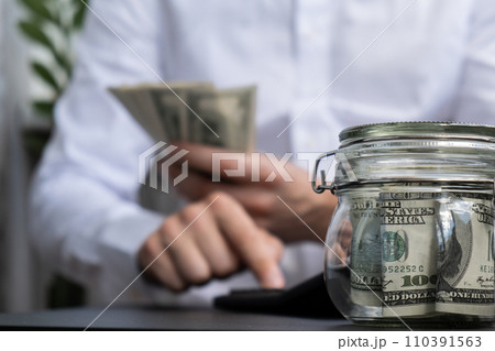 Man hands counting expenses banknotes of dollar cash on calculator. Close up of hands unrecognizable Businessman. Save up budget investment concept. American bucks fund savings Man hands counting expenses banknotes of dollar cash on calculator. Close up of hands unrecognizable Businessman. Save up budget investment concept. American bucks fund savings 110391563