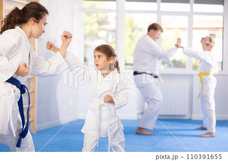 Mom trains daughter to do kicks at karate lessons 110391655