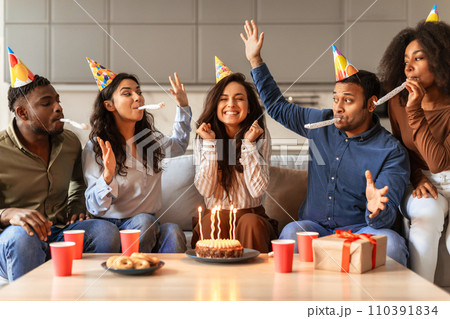 Diverse friends in festive hats making birthday wish indoor 110391834