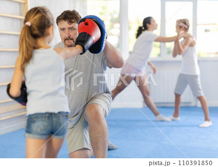 Girl hitting the focus mitts held by his boxing father 110391850
