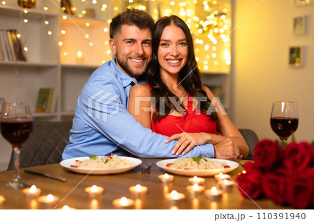 Happy couple embracing at dinner with wine and roses, warm bokeh lights Happy couple embracing at dinner with wine and roses, warm bokeh lights 110391940
