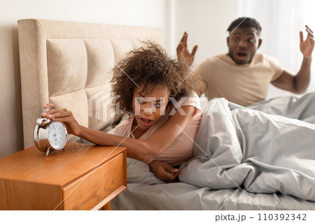 Shocked black couple missed alarm clock being late in bedroom 110392342