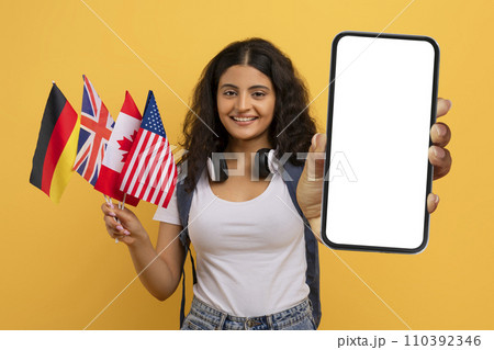 Cheerful young indian woman student with many different flags, smartphone 110392346