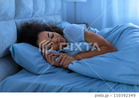 Peaceful black lady asleep napping in domestic bedroom at night Peaceful black lady asleep napping in domestic bedroom at night 110392349