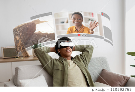 Virtual reality bridges gap as young black guy in VR glasses enjoys lifelike video chats from the comfort of his home 110392765