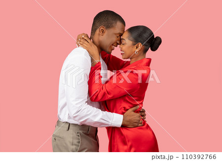 Intimate african american couple in loving embrace on soft pink backdrop Intimate african american couple in loving embrace on soft pink backdrop 110392766