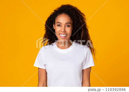 Black young lady with curly hair expressing positivity, yellow background Black young lady with curly hair expressing positivity, yellow background 110392896
