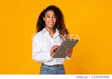 Cheerful African American lady engaging with digital tablet in studio Cheerful African American lady engaging with digital tablet in studio 110392898