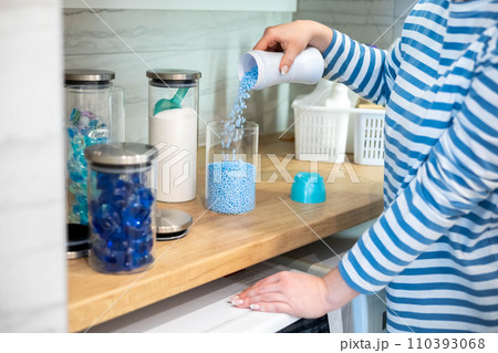 Female housewife hands sprinkle dry blue granular laundry conditioner glass can storage organizing Female housewife hands sprinkle dry blue granular laundry conditioner glass can storage organizing 110393068