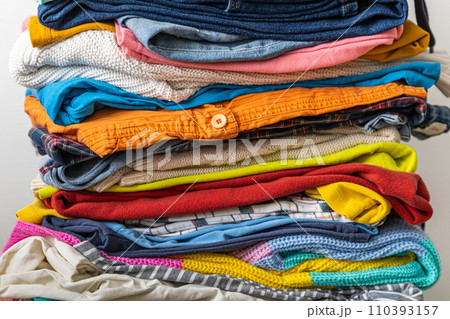 A very tall stack of folded colored clothes for charity, washing, ironing and sorting. 110393157