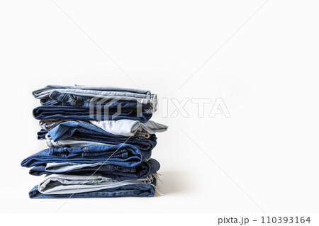 Stack of various shades of blue jeans on white background Stack of various shades of blue jeans on white background 110393164