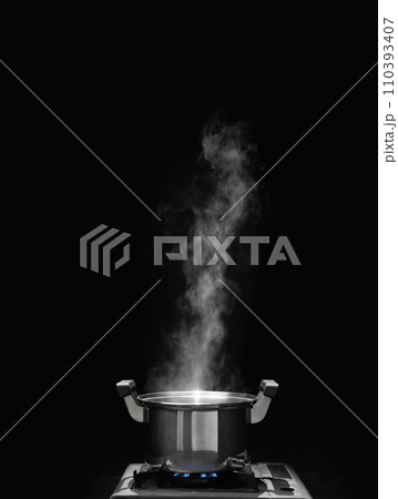 steam over cooking pot in kitchen on dark background. steam over cooking pot in kitchen on dark background. 110393407