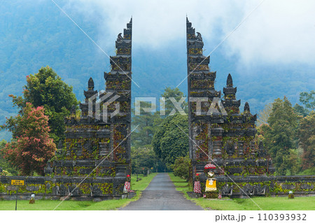 Balinese traditional gate against the background of mountains with clouds on the popular tourist island of Bali. Balinese traditional gate against the background of mountains with clouds on the popular tourist island of Bali. 110393932
