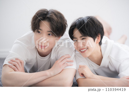 リビングの絨毯に寝転んでくつろぐ笑顔の若いカップル 110394419