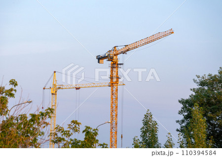 Construction crane stands tall and poised atop a power line in the midst of a bustling city. Construction crane stands tall and poised atop a power line in the midst of a bustling city. 110394584