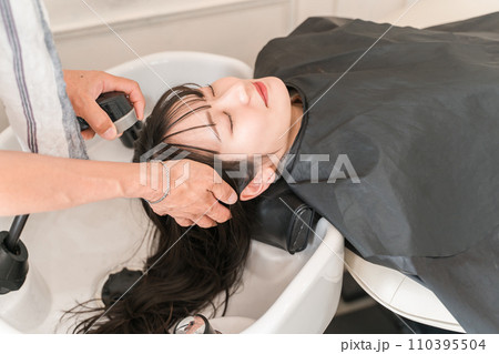 美容室のシャンプー台でシャンプーする女性と美容師・スタイリスト 美容室のシャンプー台でシャンプーする女性と美容師・スタイリスト 110395504
