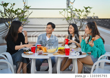 Group of young friends having fun talking and drinking at rooftop party in evening 110395793
