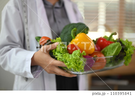 Cropped shot of dietitian holding a bowl of vegetables for healthy eating and diet Cropped shot of dietitian holding a bowl of vegetables for healthy eating and diet 110395841