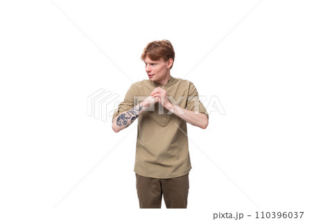 a young slender red-haired caucasian guy dressed in a khaki short-sleeve shirt holds his hands near 110396037