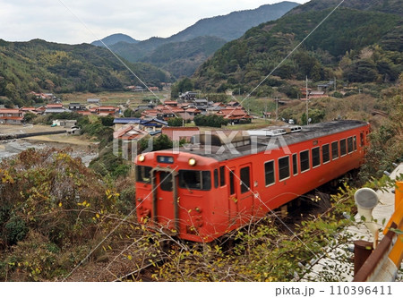 のんびりと山陰の集落を後に走る40系気動車 110396411