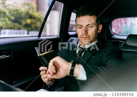 後部座席に乗りスケジュールを確認する外国人ビジネスマン（白人男性） 110398558