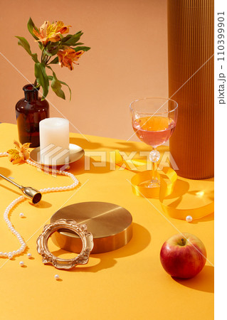 Golden podium in round shaped arranged with pearls, a pot of flowers, a candle and a glass of wine. Glamour minimal pedestal for beauty, cosmetic product presentation 110399901