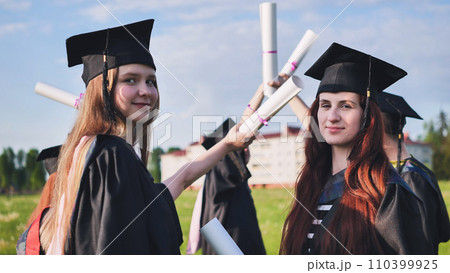Portraits of graduating girls in black robes on the street. 110399925