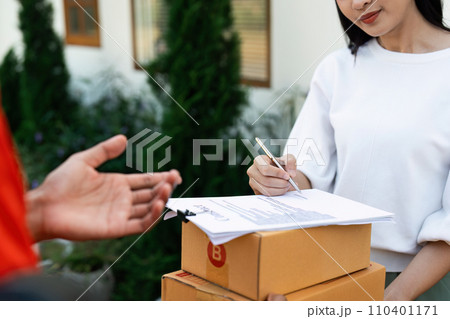 Young woman signature in document to receive package from professional delivery man at home Young woman signature in document to receive package from professional delivery man at home 110401171