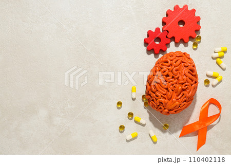 Orange human brain model with pills and gears 110402118