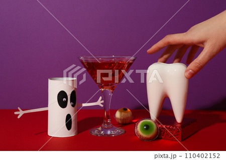Big tooth with Halloween accessories, on a colored background. 110402152