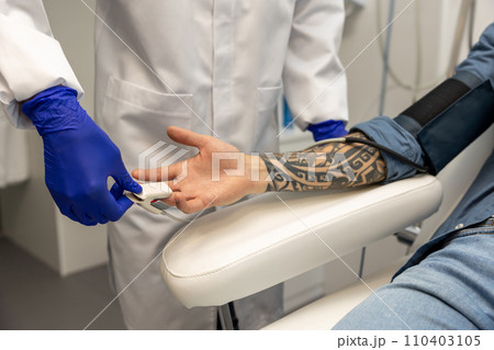Nurse measuring pressure and oxygen level in male finger. Nurse measuring pressure and oxygen level in male finger. 110403105