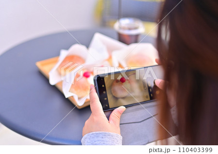 カフェスイーツをスマホで撮影する女性 110403399