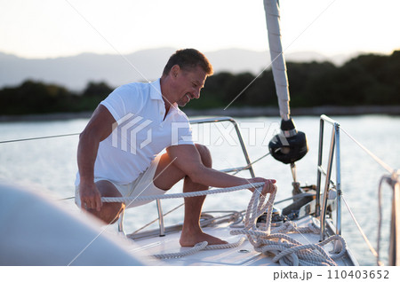 Smiling man on a yacht fixing the rope Smiling man on a yacht fixing the rope 110403652