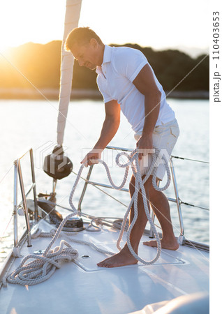 Smiling man on a yacht fixing the rope Smiling man on a yacht fixing the rope 110403653