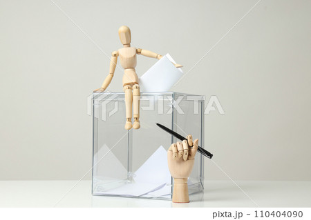 Transparent box, voting papers, wooden man and hand with pen on gray background 110404090