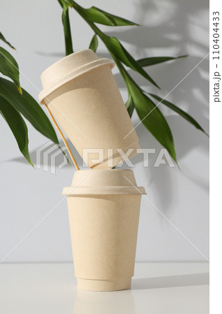 Paper cups with lids and green leaves Paper cups with lids and green leaves 110404433