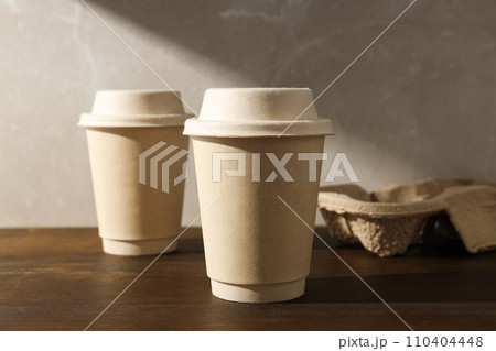 Paper cups with lids on a wooden table Paper cups with lids on a wooden table 110404448