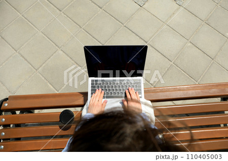The girl works on a laptop while sitting on a bench 110405003