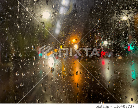 Rain bokeh road lights. Abstract shot of evening city traffic bokeh. Multicolored lights of the evening city and passing cars through a wet rainy window. 110405737
