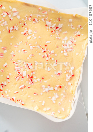 Removing candy cane fudge from a square cheesecake pan lined with parchment. Removing candy cane fudge from a square cheesecake pan lined with parchment. 110407607