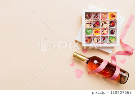 Bottle of red wine on colored background for Valentine Day with gift and chocolate. Heart shaped with gift box of chocolates top view with copy space Bottle of red wine on colored background for Valentine Day with gift and chocolate. Heart shaped with gift box of chocolates top view with copy space 110407668